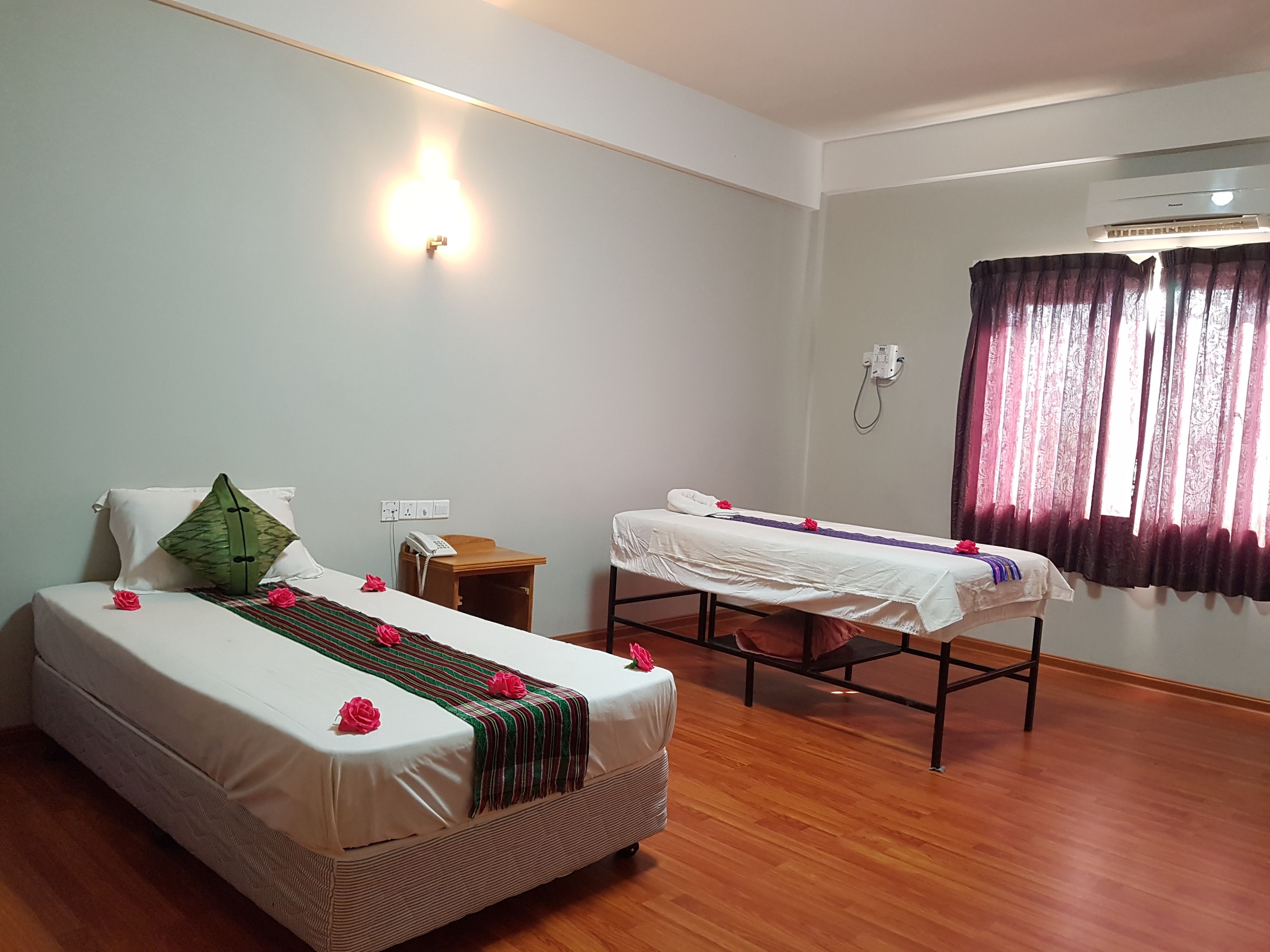 A room with two beds, a small table, a phone, and an air conditioning unit.