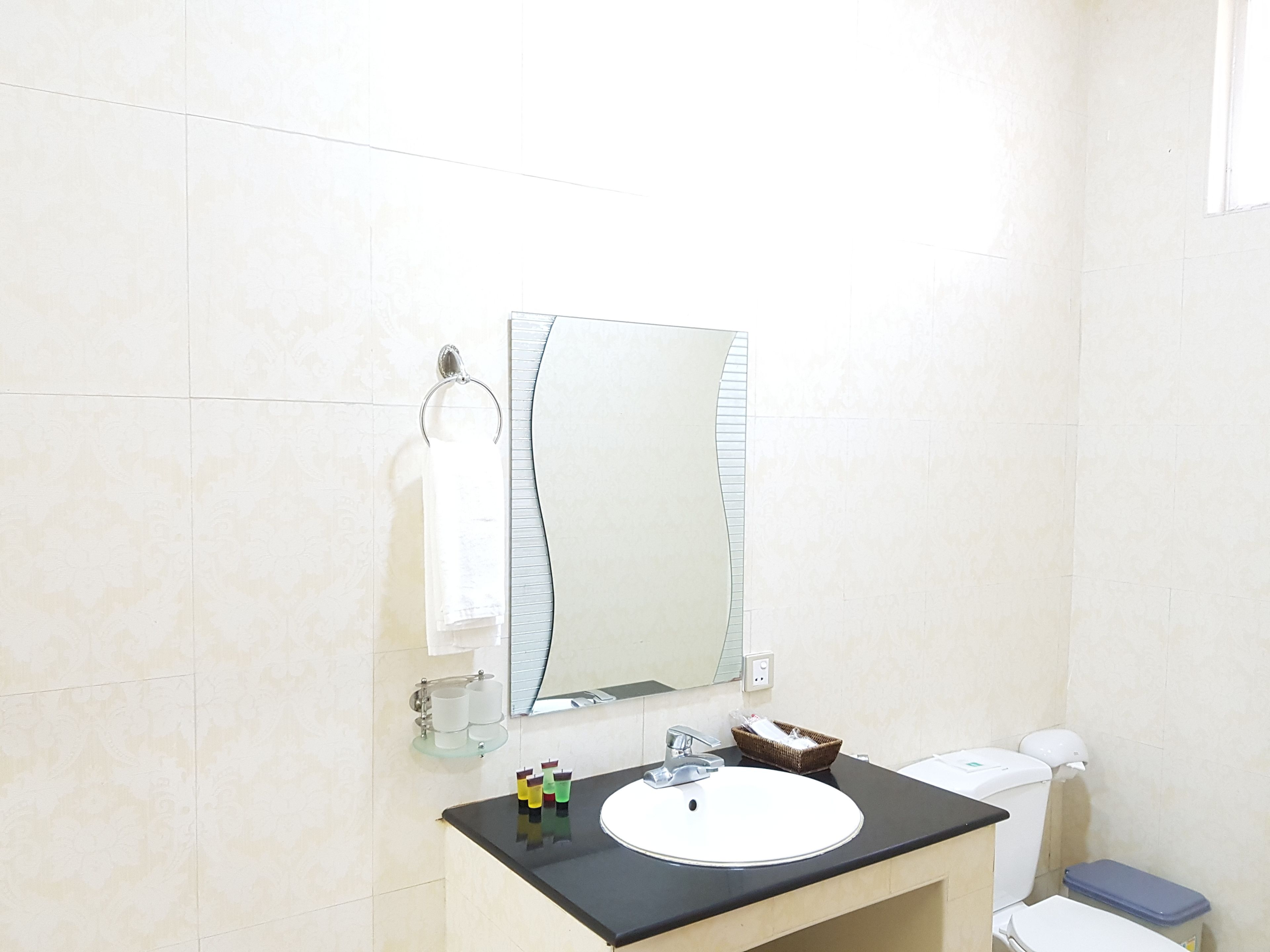 A bathroom with a sink, mirror, toilet, and a small basket on the counter.