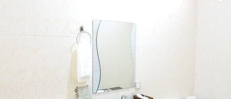 A bathroom with a sink, mirror, toilet, and a small basket on the counter.