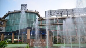 Een hotel met een fontein ervoor, grote glasramen en een bord boven de ingang.
