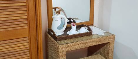 A small room with a wooden cabinet containing a kettle, cups, and a tray.
