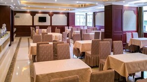 Una sala conferenze di un hotel con diversi tavoli e sedie, un televisore a schermo piatto e una grande finestra.