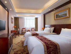 Una habitación de hotel con dos camas, televisión, escritorio y silla.