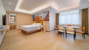 Una camera d'albergo con un letto, un comodino, una lampada e un quadro che raffigura un panorama urbano.