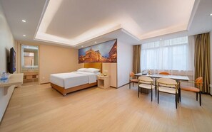 Une chambre d’hôtel avec un lit, une table de chevet, une lampe et un tableau représentant un paysage urbain.
