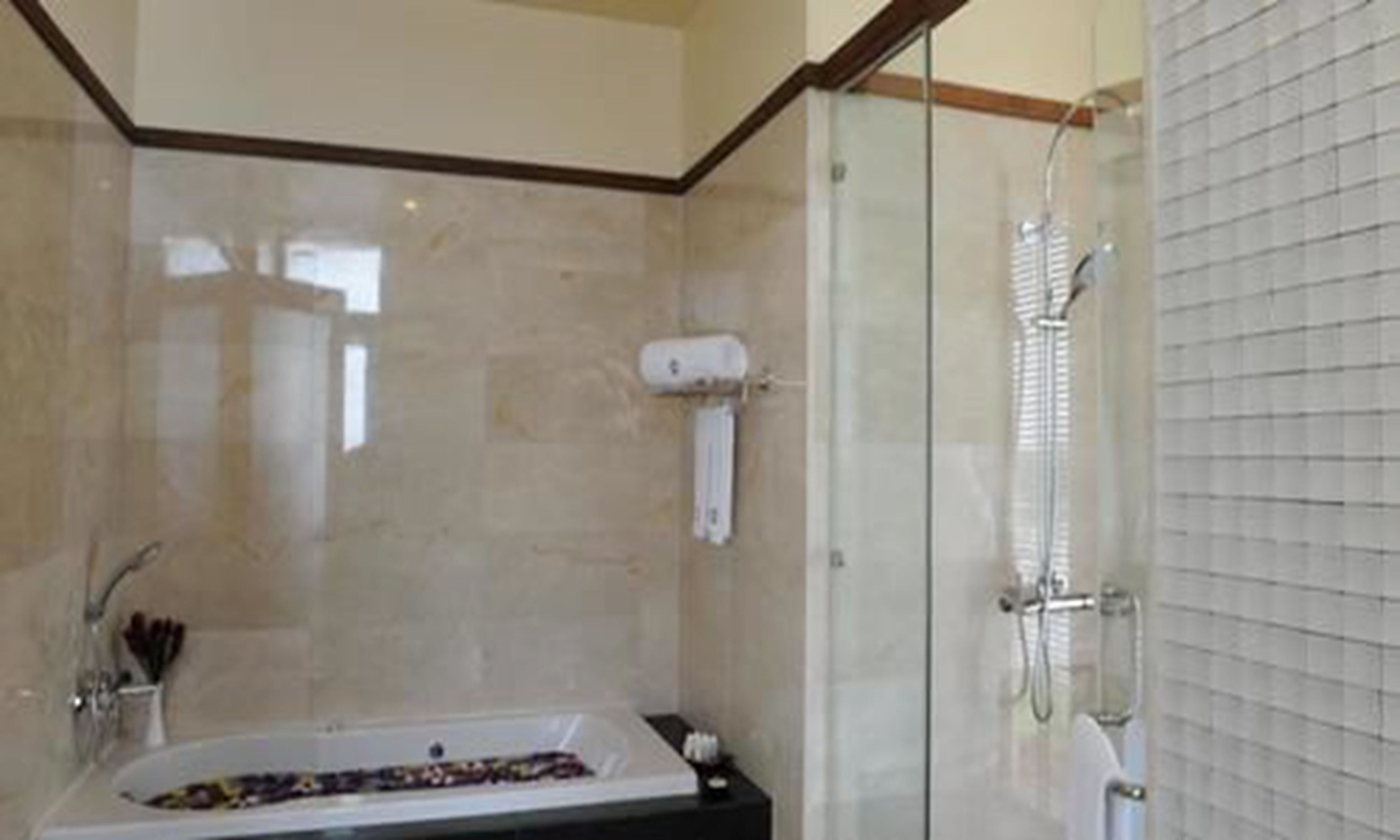 A modern bathroom with a glass-enclosed shower, a bathtub, and a vanity with toiletries.