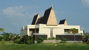 Un edificio moderno con un diseño triangular único, rodeado de exuberante vegetación.