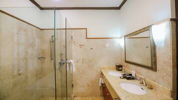 Un baño con cabina de ducha de vidrio, dos lavabos y un espejo grande.