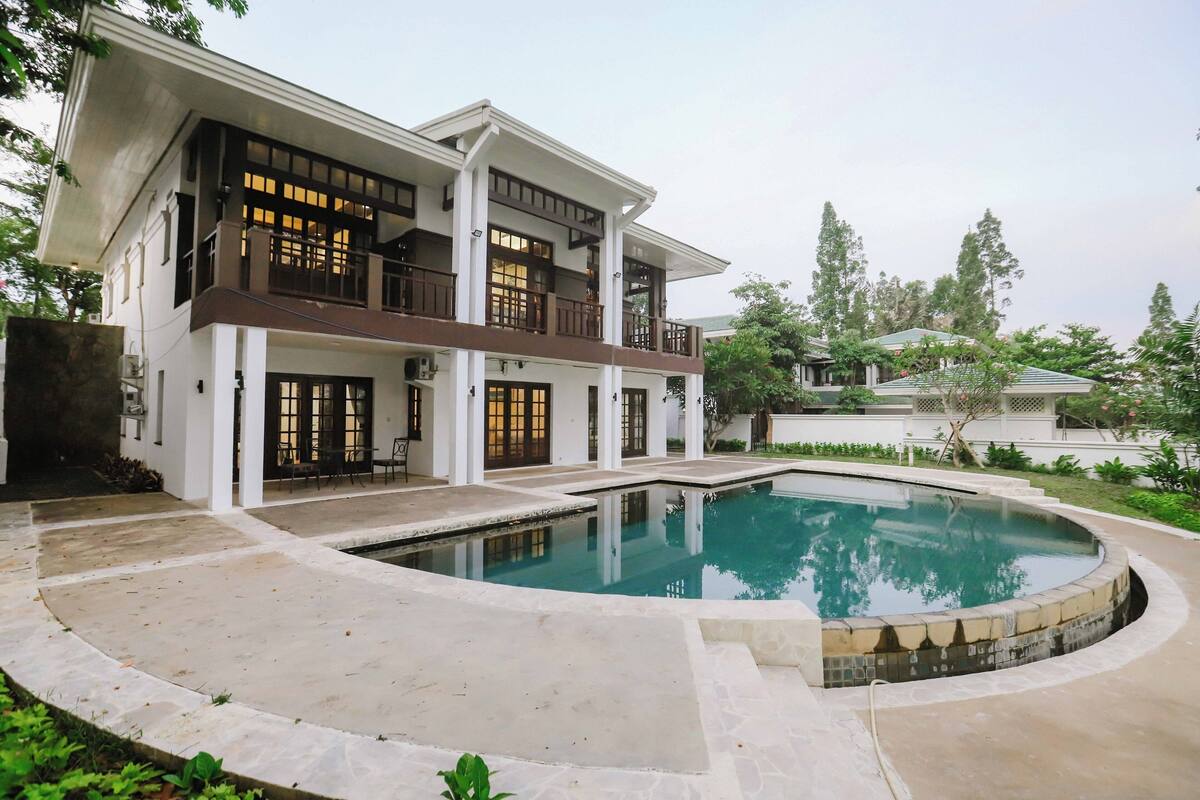 A two-story building with a swimming pool, large windows, and a balcony.