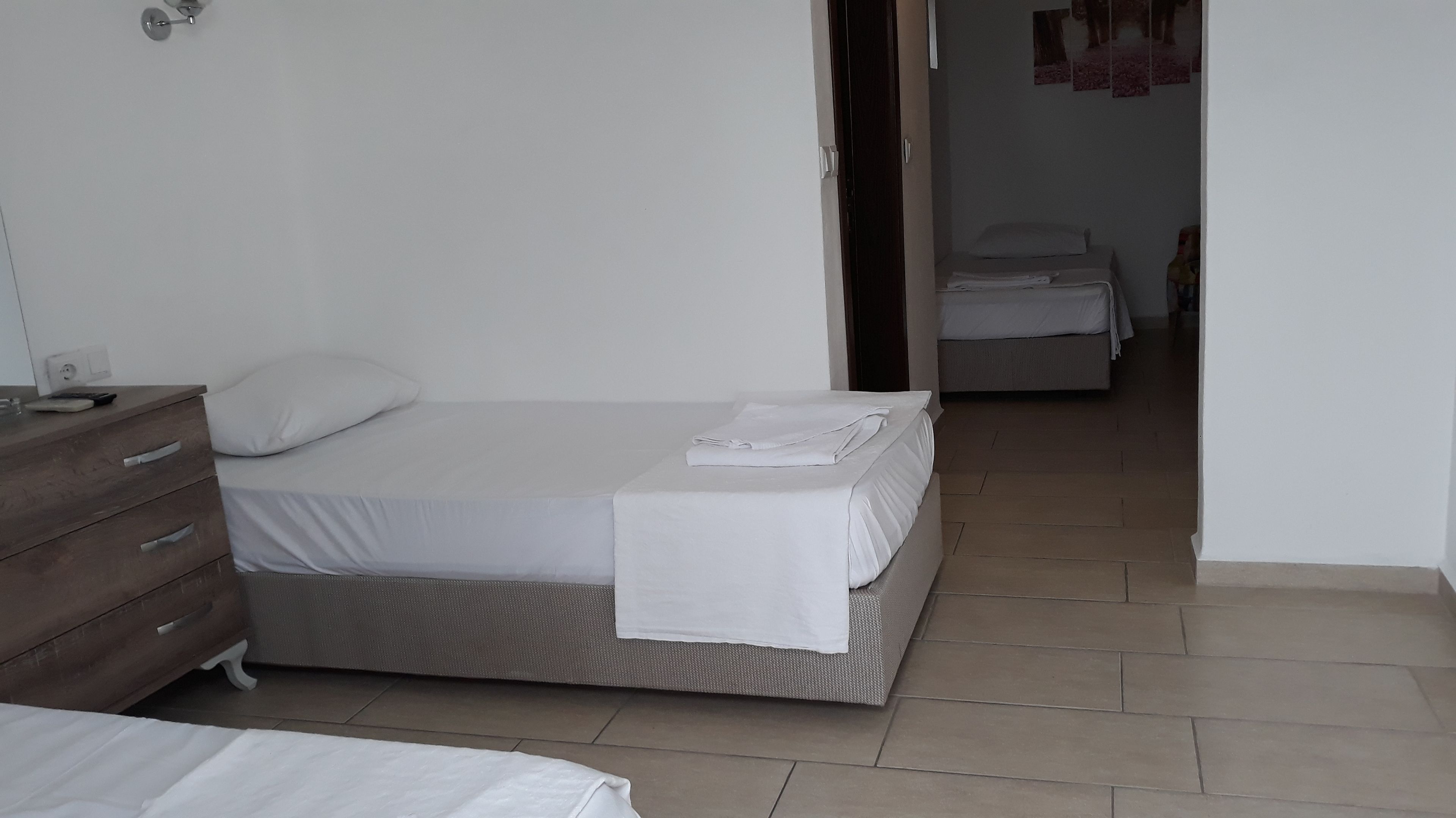 A bedroom with a bed, a wooden dresser, and a bathroom visible through an open door.