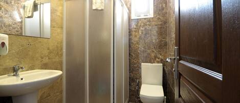 Un baño con ducha, lavabo, inodoro y puerta de madera.