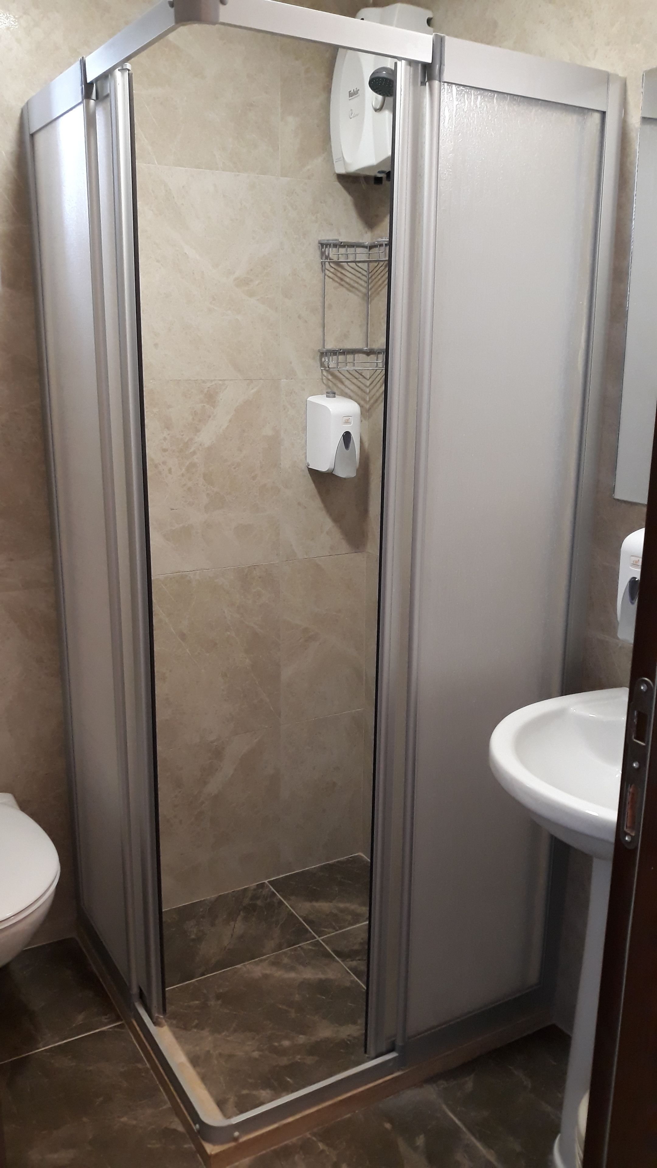 Une cabine de douche avec une porte en verre, des toilettes et un lavabo.