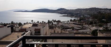 A coastal cityscape with a view of the sea and distant mountains.