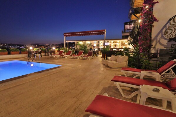 Zona de piscina en la azotea con sillones de descanso y un bar.