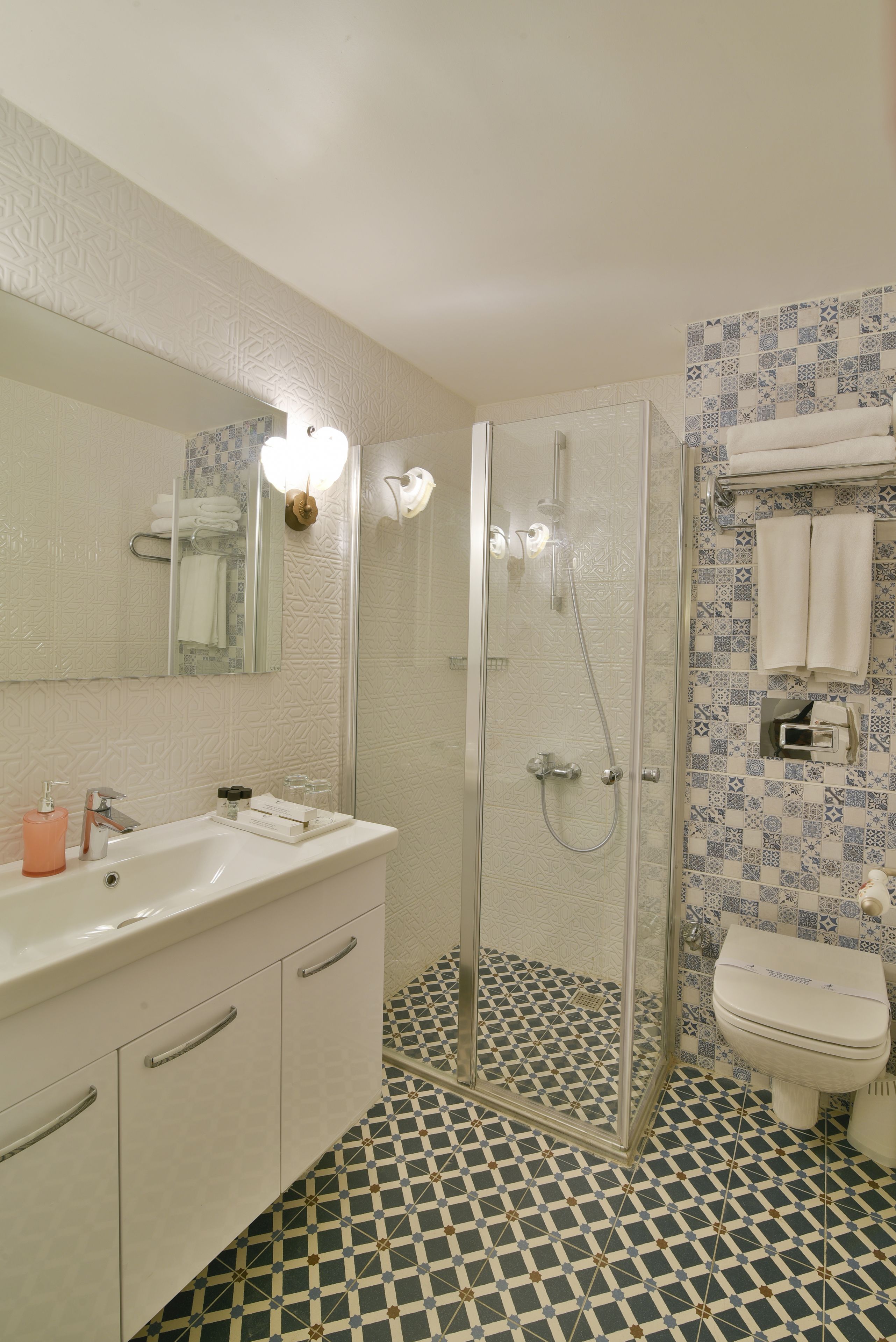 A bathroom with a glass-enclosed shower, a white sink, and a toilet.