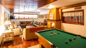 Una sala de estar acogedora con una mesa de billar, asientos cómodos y una chimenea.