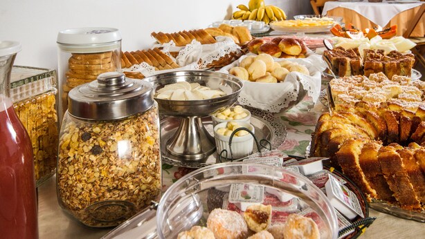 Una mesa de bufé con diversos alimentos, como pasteles, frutas y una variedad de untables.