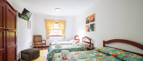 Habitación de hotel con dos camas individuales, un armario de madera, una silla, una mesita y un ventanal con cortinas.