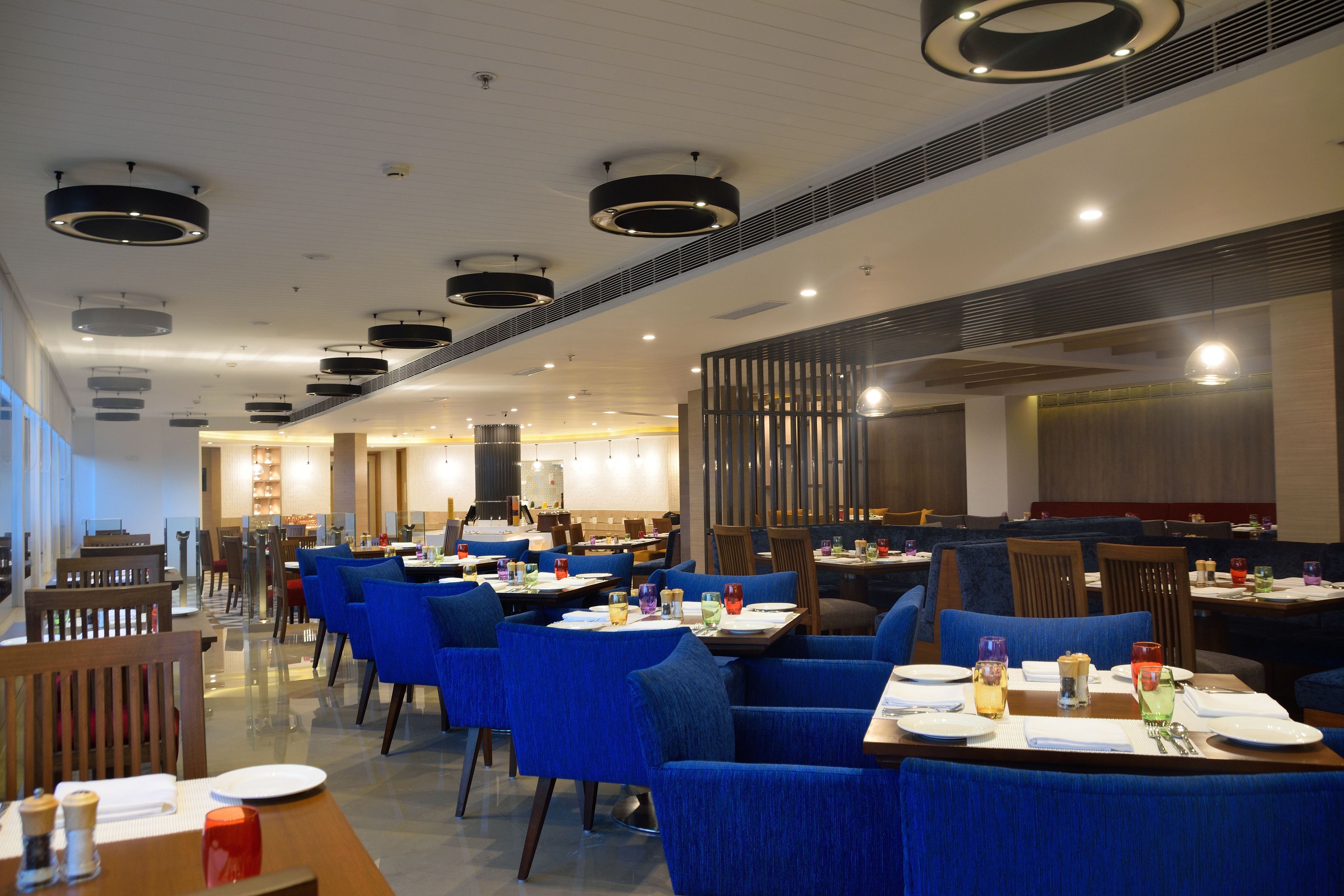 Un restaurant moderne avec des chaises à revêtement bleu, des tables rondes et des luminaires contemporains.