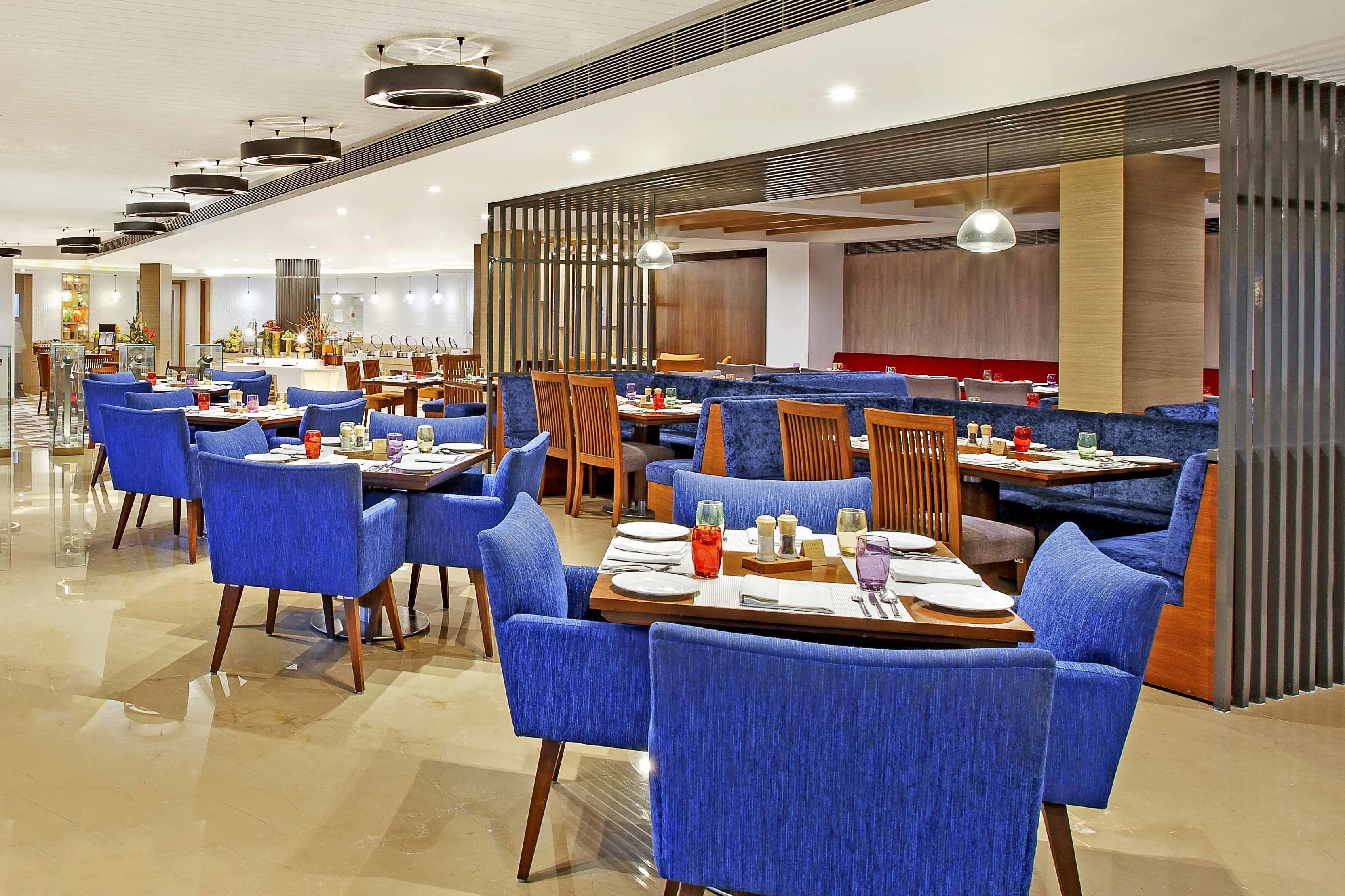 Un restaurante moderno con sillas tapizadas en azul, mesas, detalles de madera y un diseño contemporáneo.