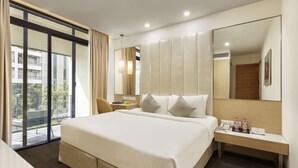 A modern hotel room with a large bed, a bedside table with amenities, a mirror, and a view of the outside.