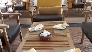 A dining area with wooden tables, chairs, and a central decorative bowl. - Traveller's Home Hotel (Thissamaharama)
