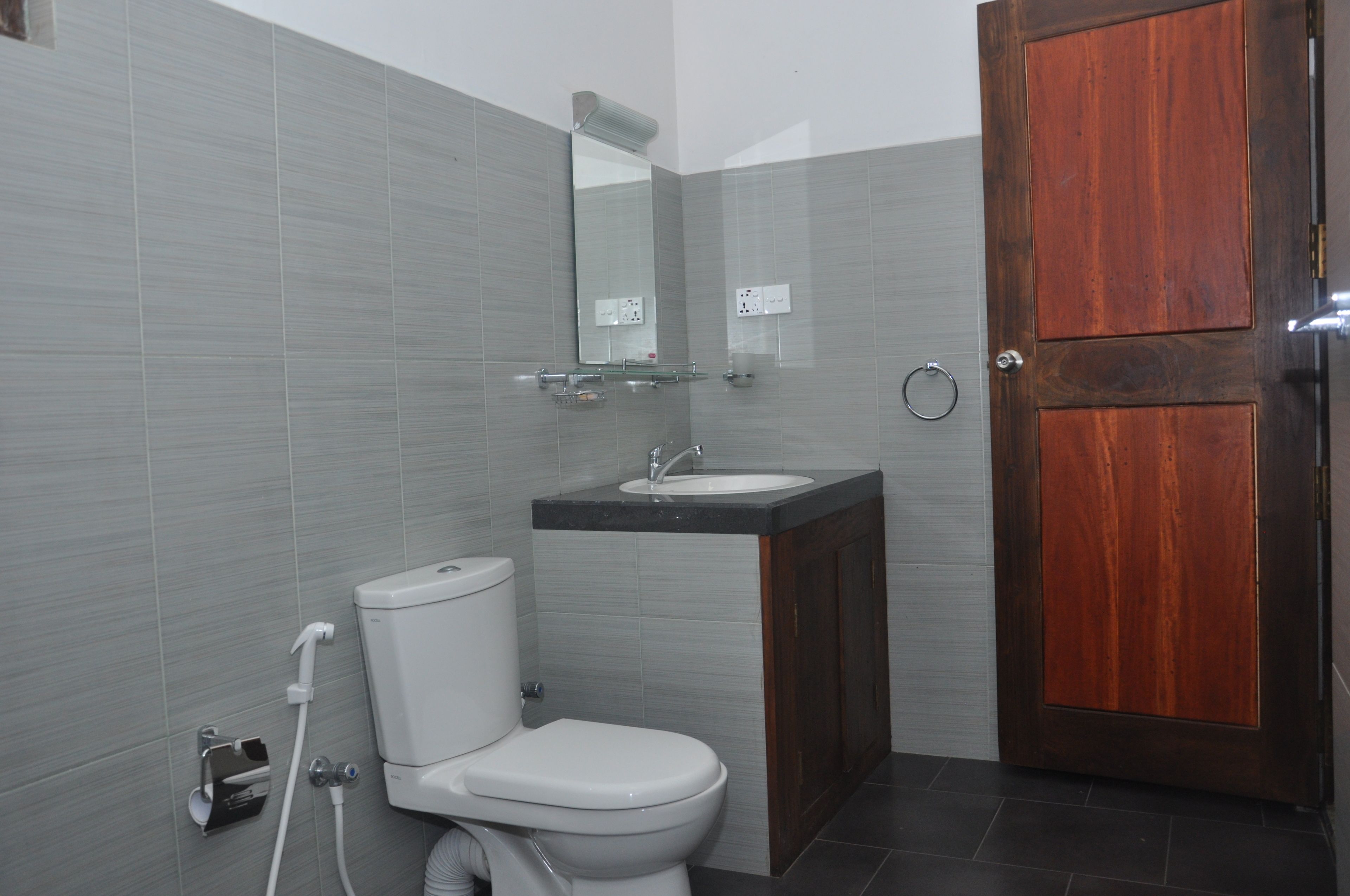 A bathroom with a toilet, sink, and mirror.