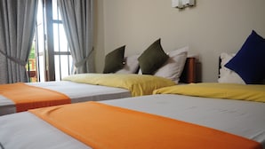 A hotel room with two beds, each with an orange bedspread and pillows in various colors. - Traveller's Home Hotel (Thissamaharama)