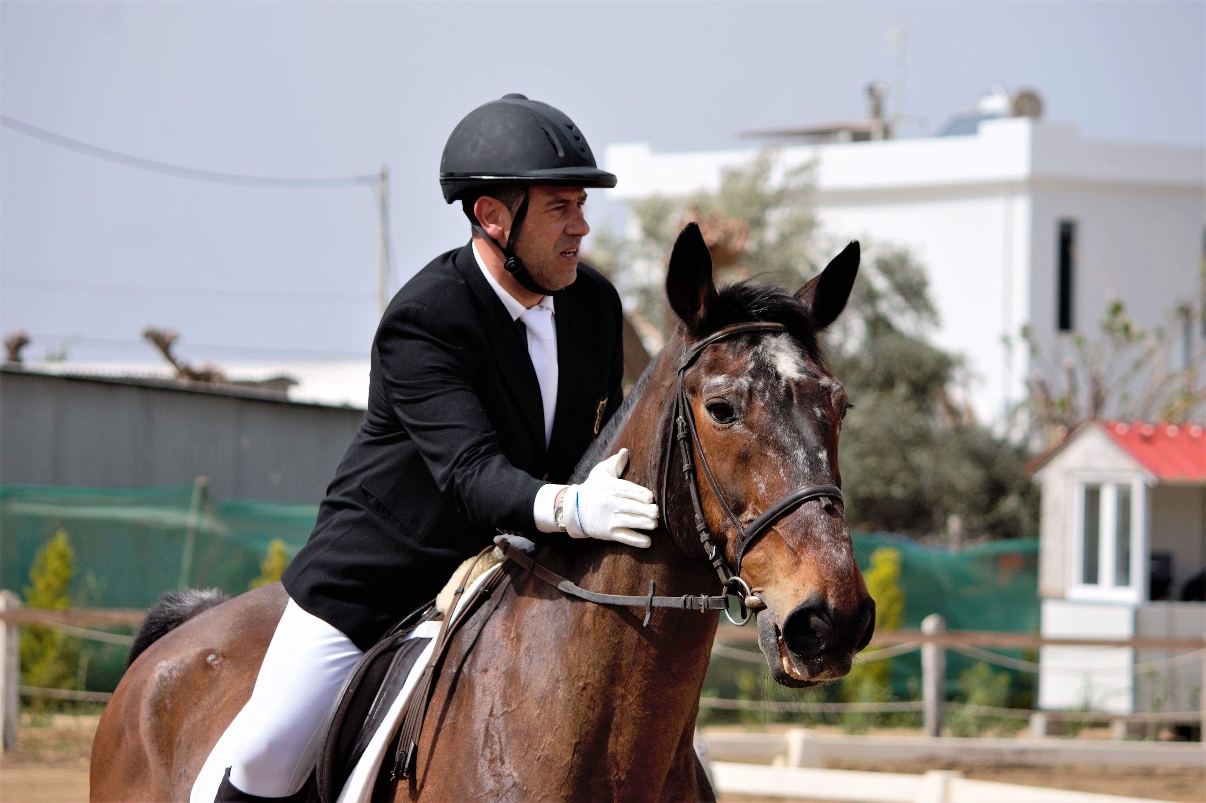 A person riding a horse in an outdoor setting with a building in the background.