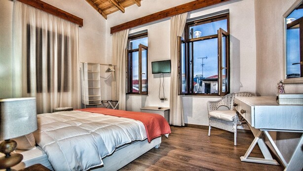 A bedroom with a bed, a desk, a chair, and large windows. - Maya's Residence (Rethymno)