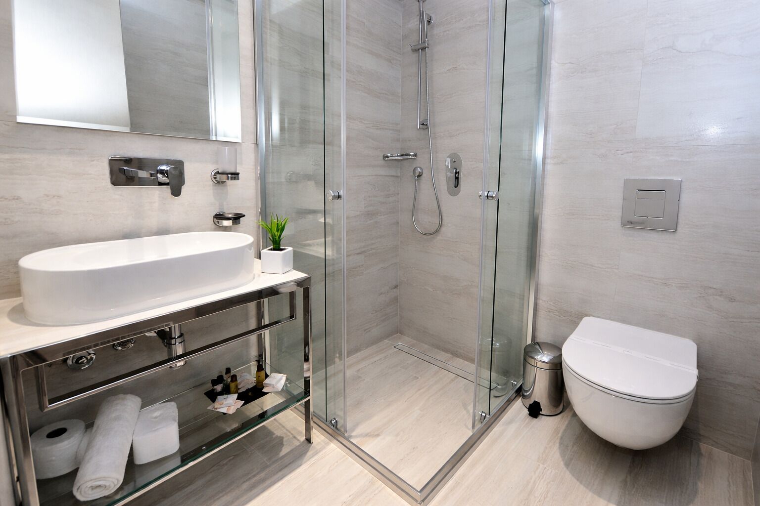A modern bathroom with a glass-enclosed shower, a white sink, and a toilet.
