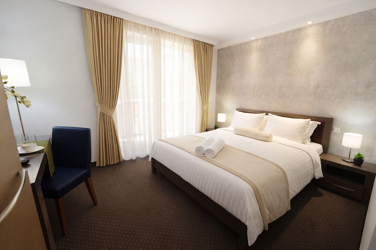 Une chambre d’hôtel avec un lit, une chaise, un bureau et une lampe.