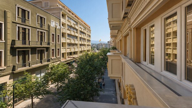 A multi-story building with balconies, a central courtyard, and a clear sky.