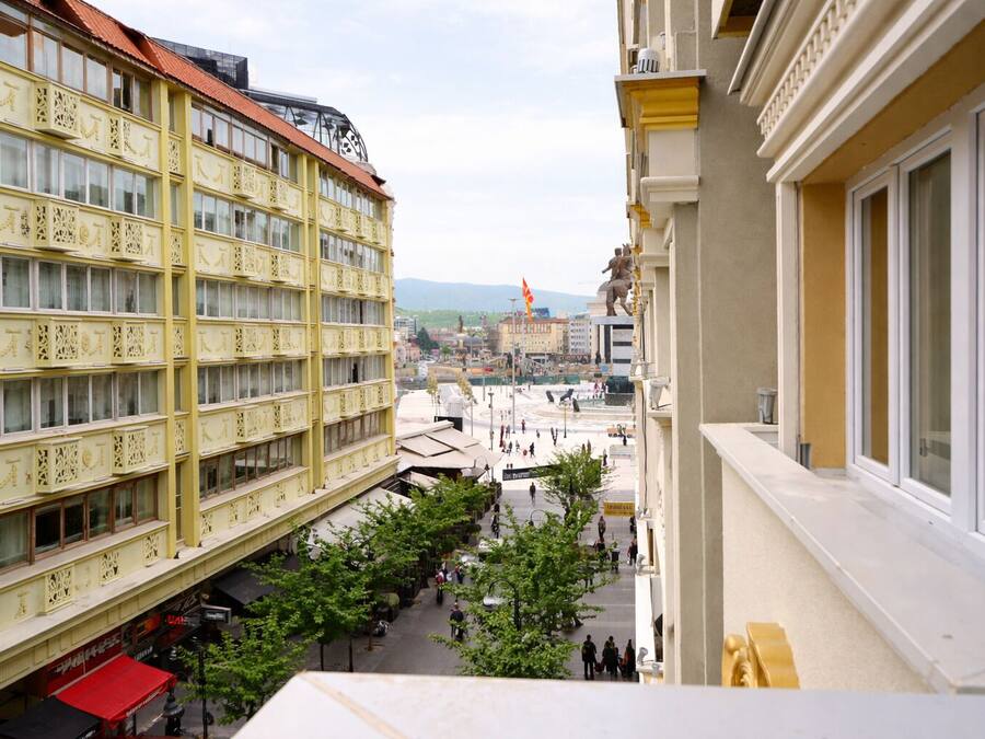 Ein mehrstöckiges Gebäude mit Balkonen, einem zentralen Innenhof und einer Statue in der Ferne.