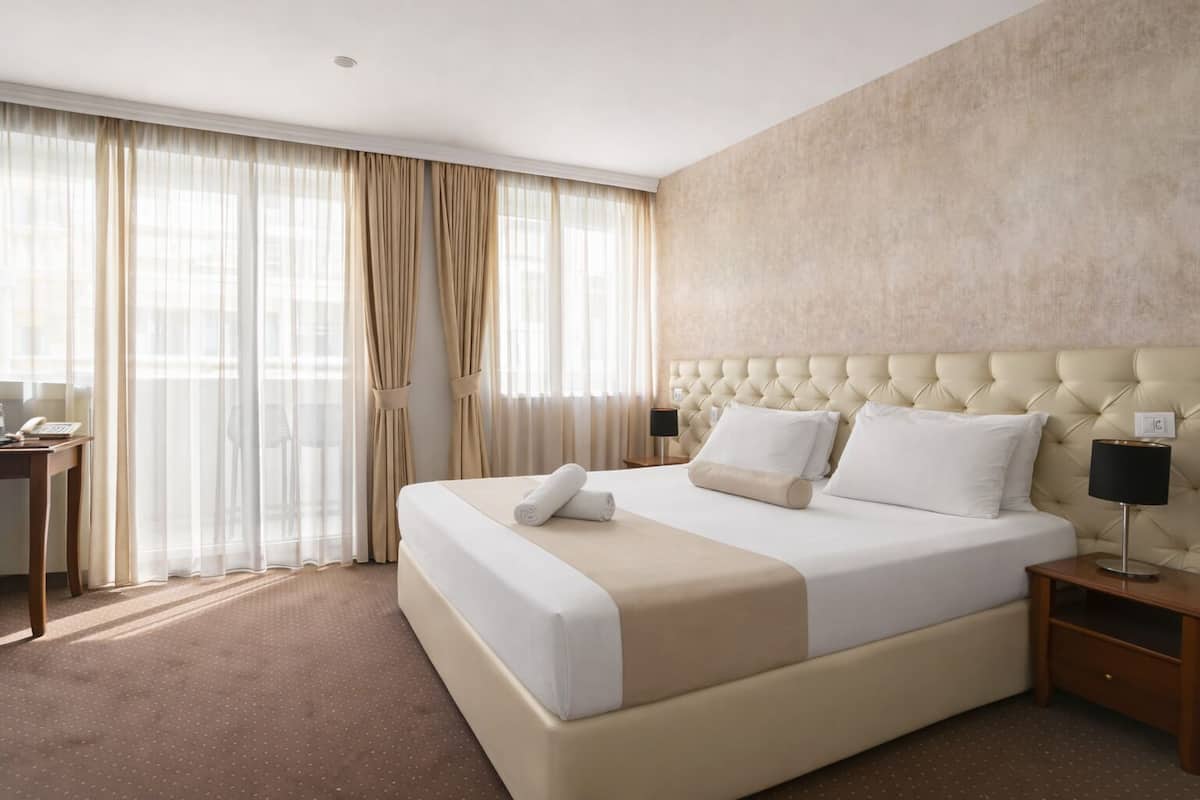 Une chambre d’hôtel avec un grand lit, un bureau et une table de chevet.