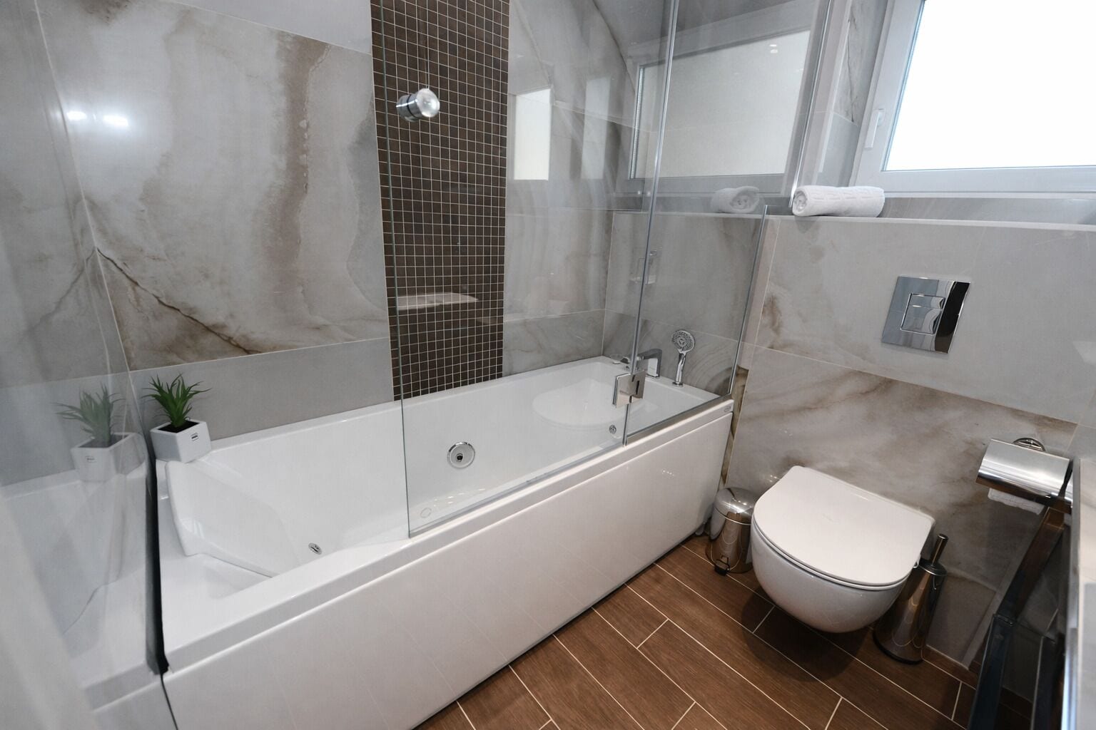 A modern bathroom with a freestanding bathtub, a toilet, and a glass-enclosed shower area.