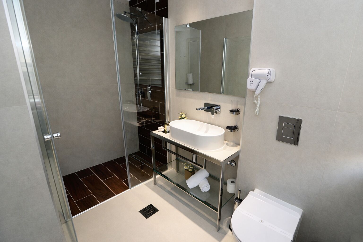 A modern bathroom with a glass shower enclosure, a white sink, and a mirror.