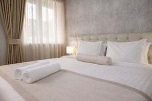 A hotel room with a large bed, a headboard, and a window with curtains. - Hotel Alexandar Square Boutique (Skopje)