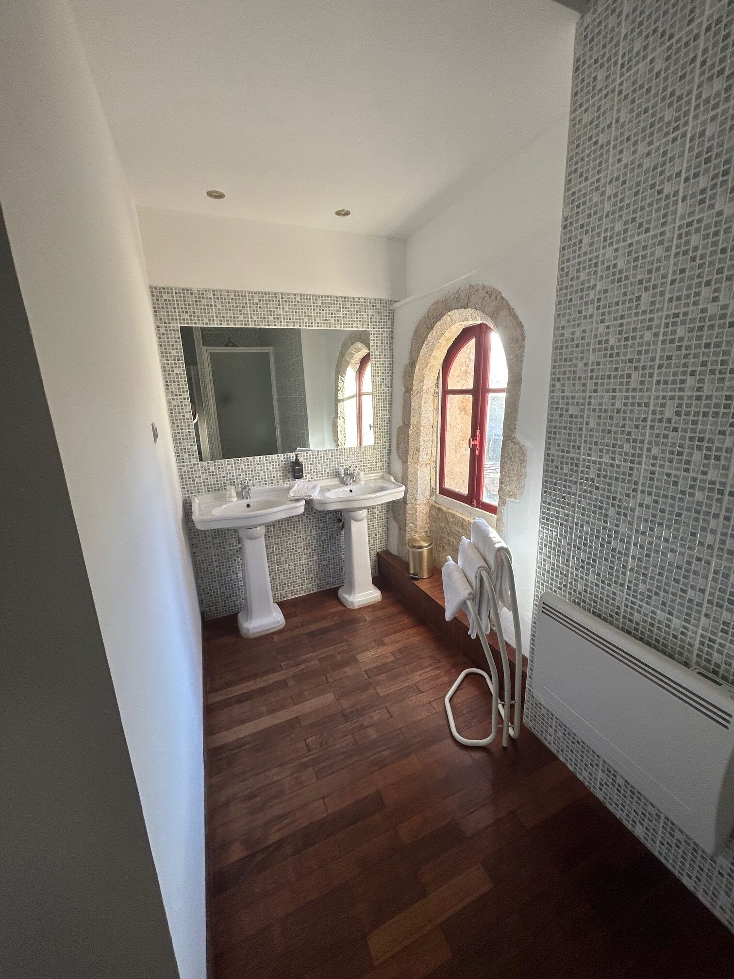 Une salle de bain avec deux lavabos, un miroir et une fenêtre à arc.