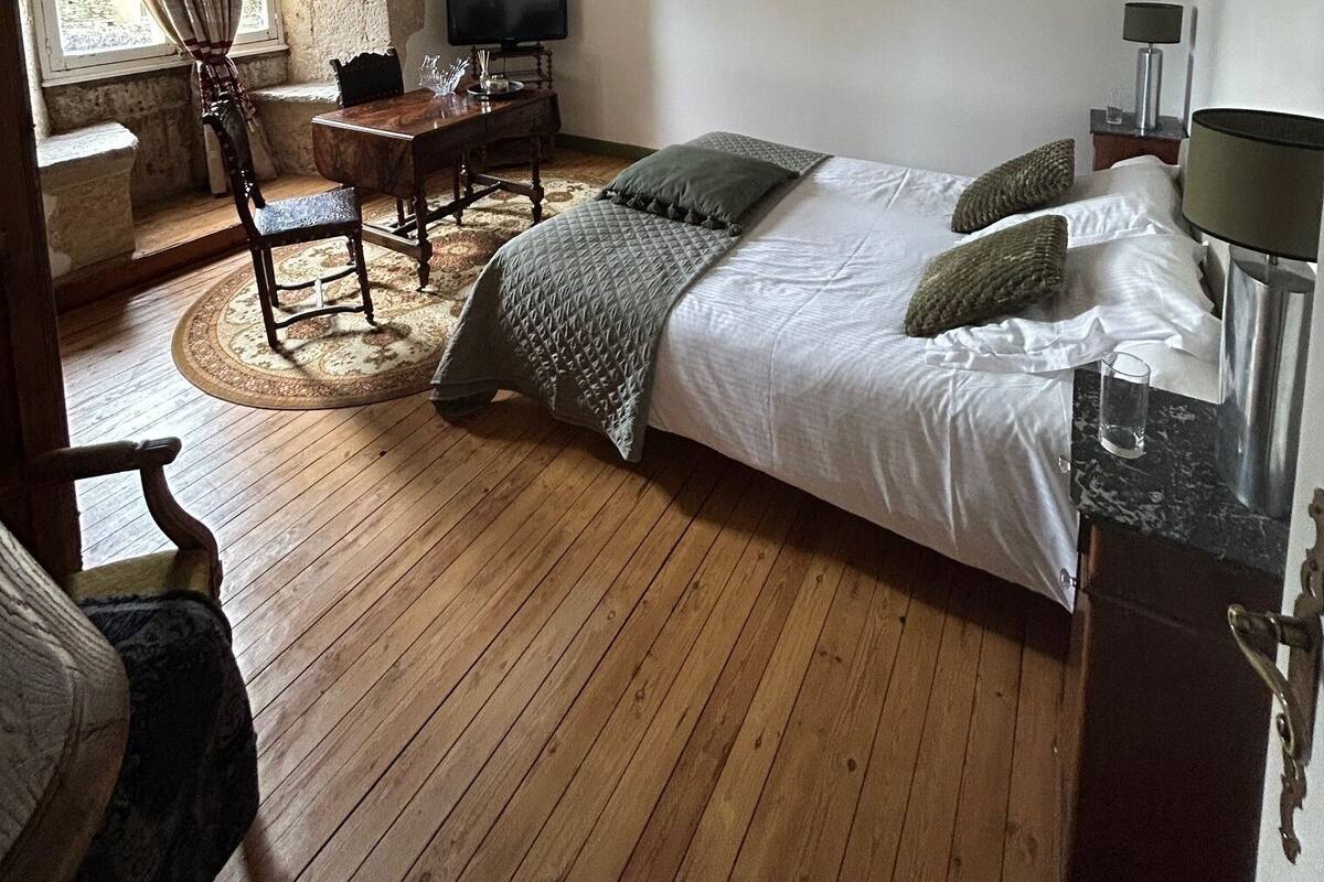 Quarto com cama, escrivaninha, cadeira e televisão.