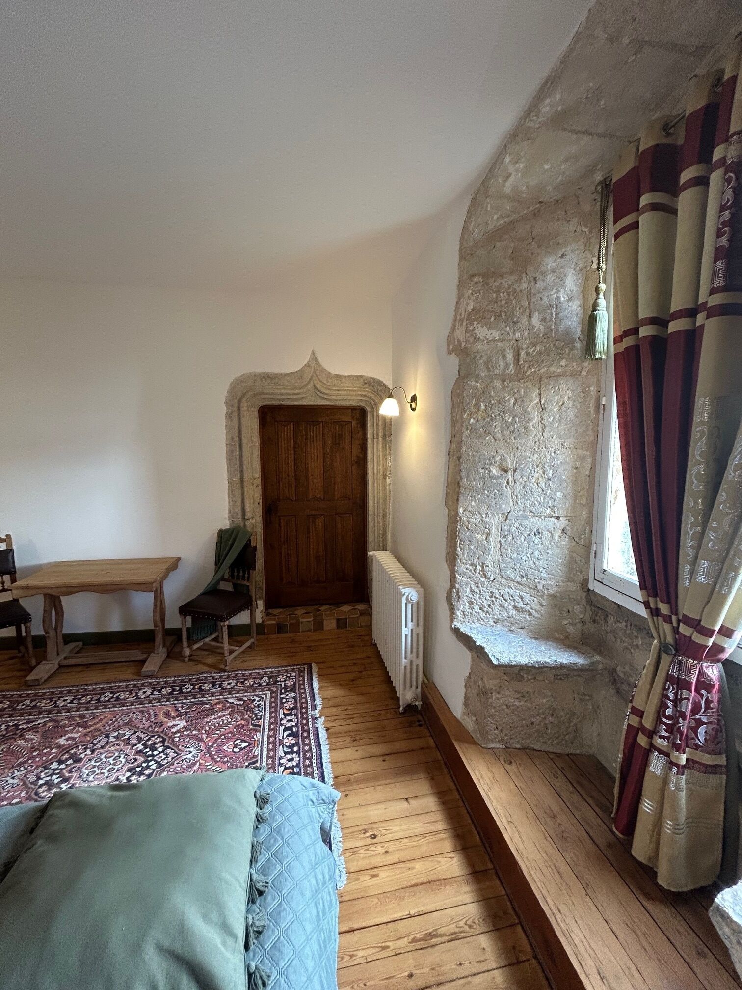 Una habitación rústica con una cama de madera, una mesita pequeña y un banco.
