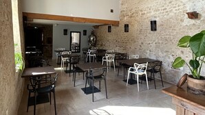 Un comedor rústico con vigas de madera, paredes de piedra y una mezcla de sillas de metal y madera.