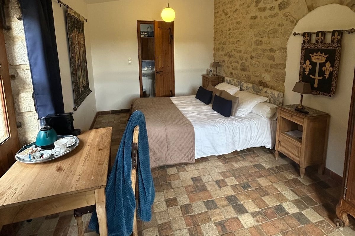 Um quarto aconchegante com cama de madeira, mesa de cabeceira, abajur e bandeja de café da manhã sobre uma mesa de madeira.