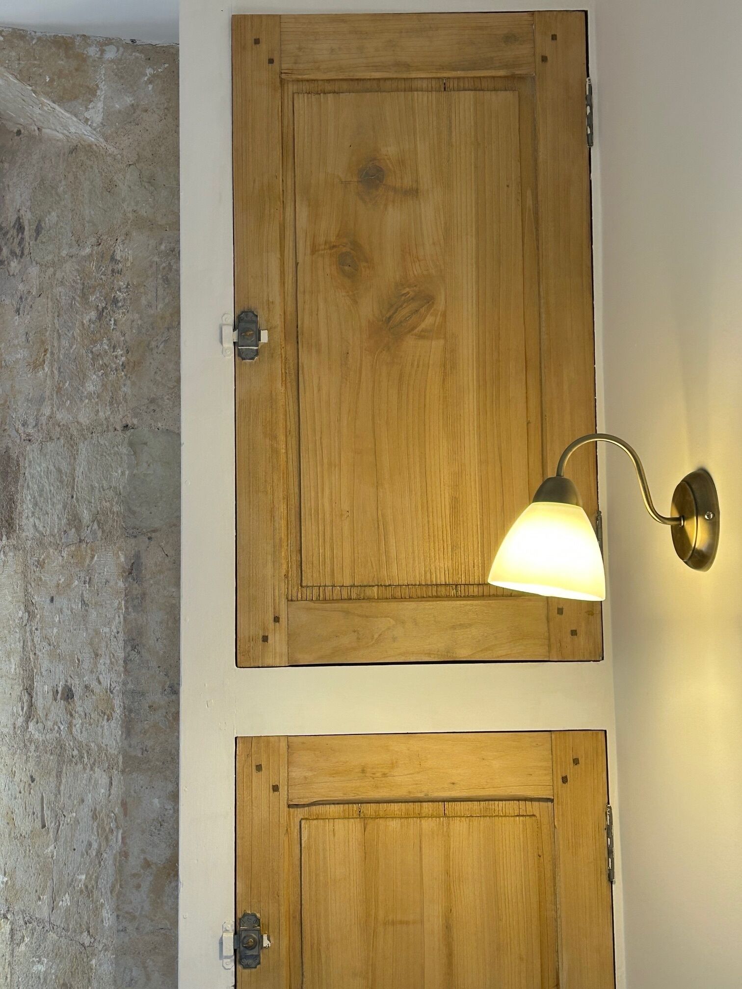 Two wooden doors mounted on a wall with a textured concrete surface to the left.