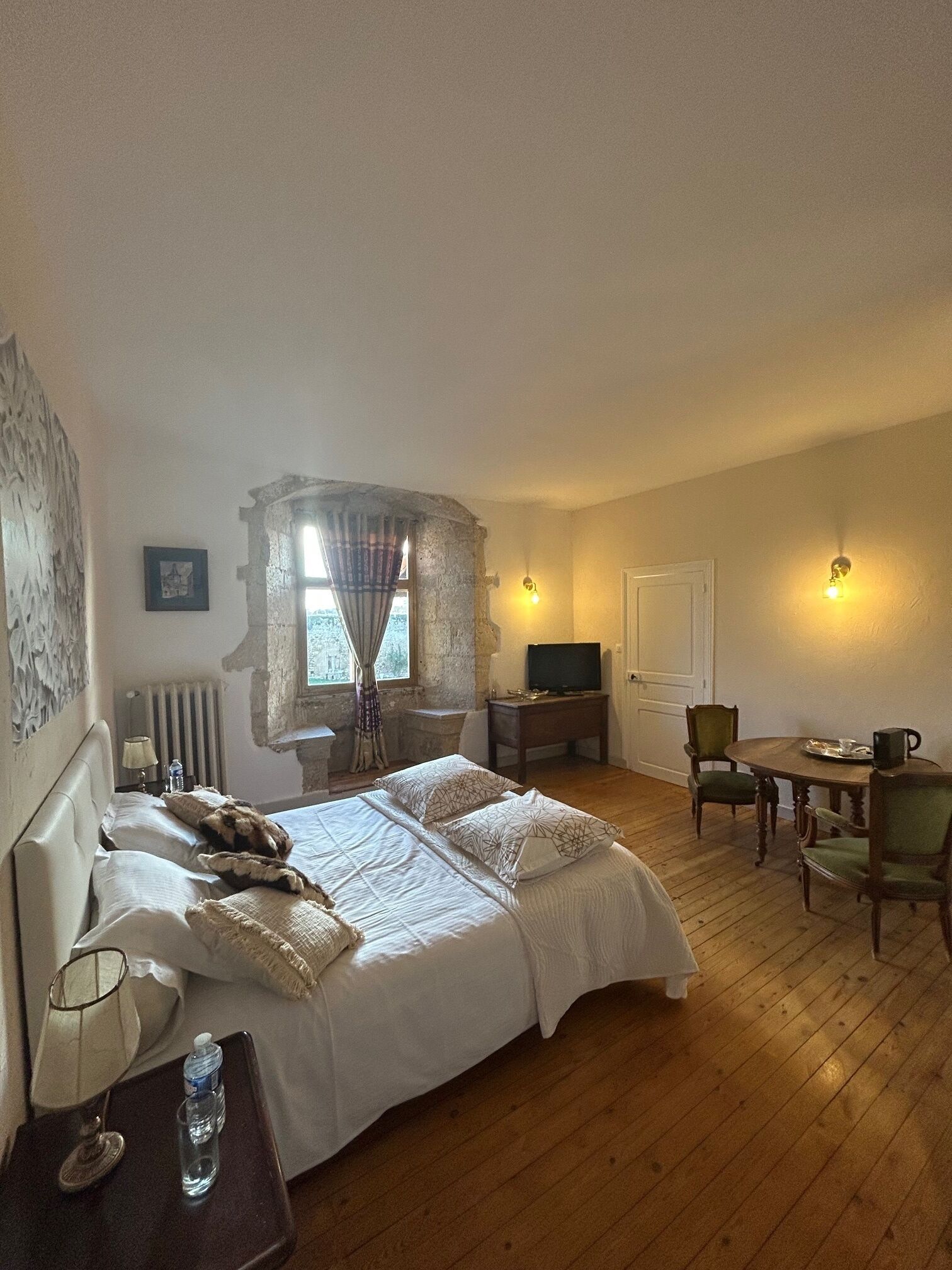 A bedroom with a large bed, a desk, a chair, and a television.