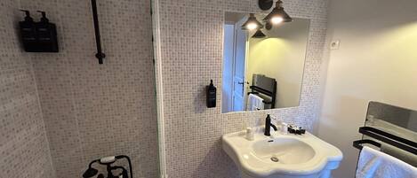 Un baño con ducha, lavamanos y espejo.