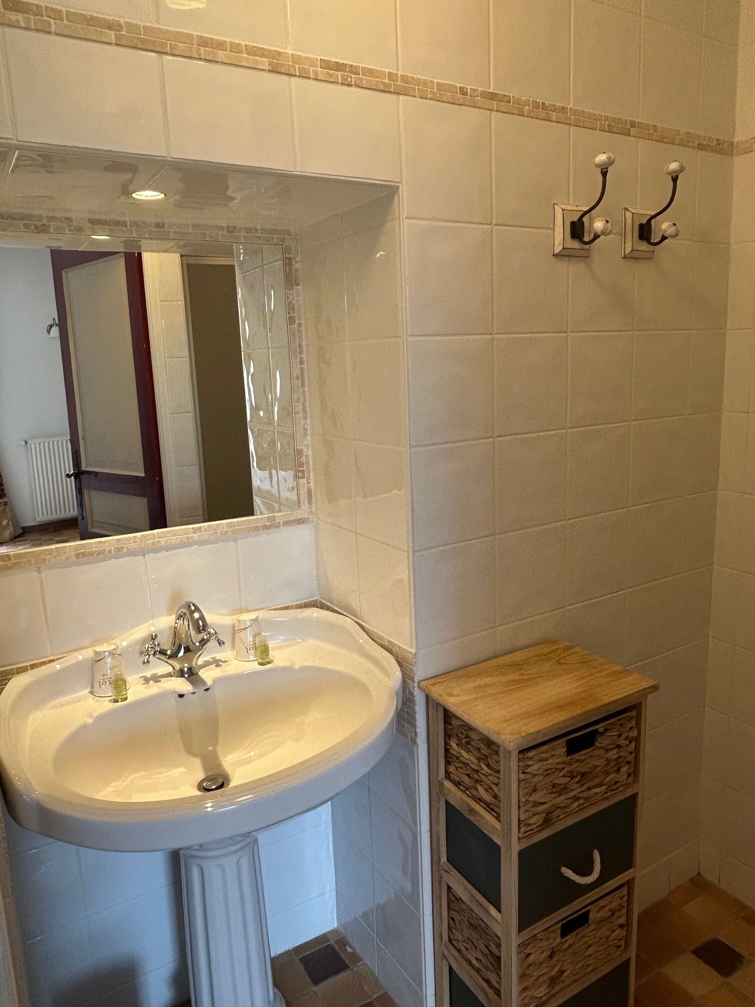 A bathroom with a sink, mirror, and two wall-mounted towel racks.