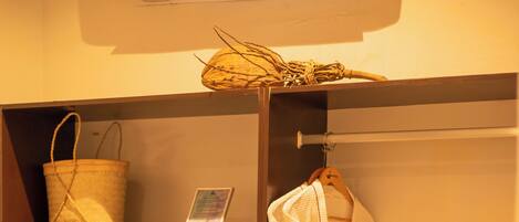 A wooden wardrobe with shelves containing folded towels, a robe, a basket, and a microwave.