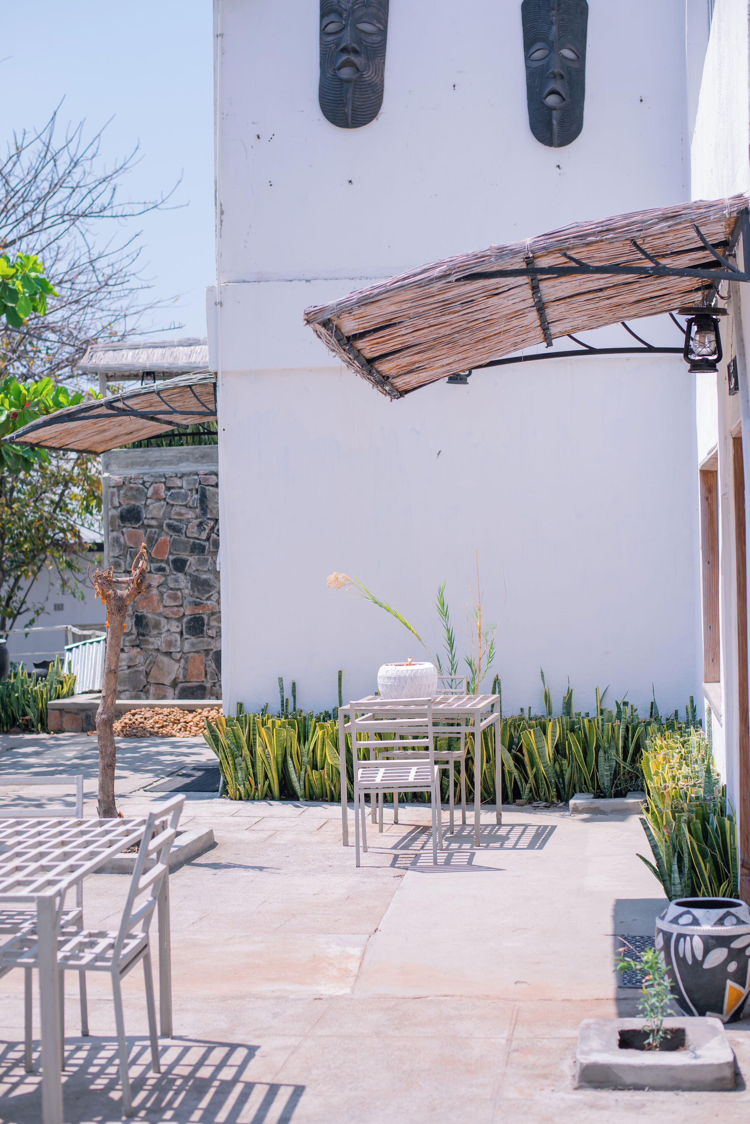 An outdoor patio area with a table and chairs, a stone wall, and decorative plants.
