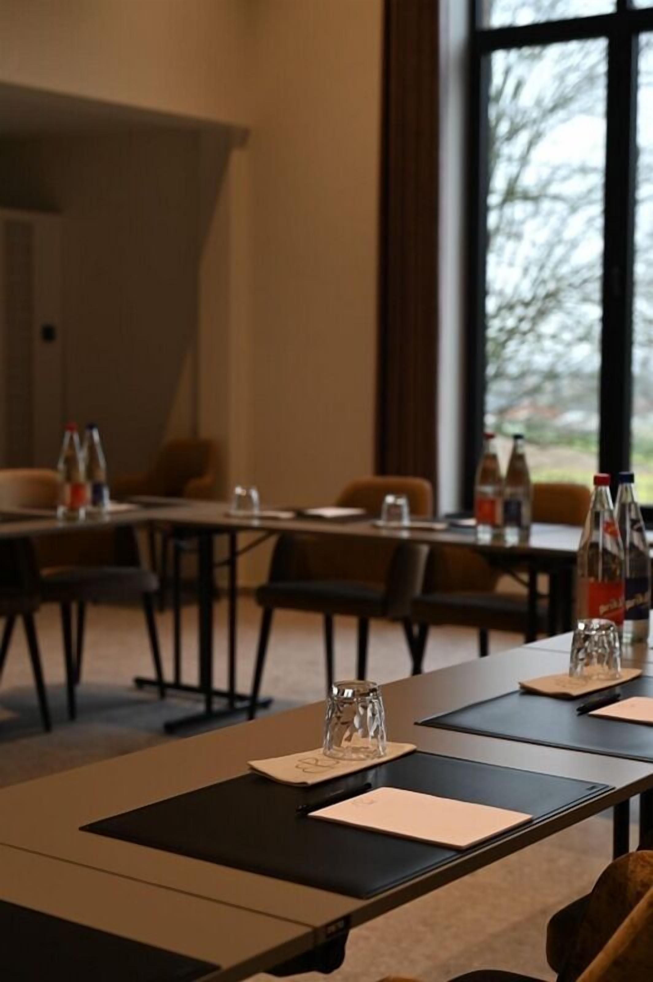 A conference room with tables, chairs, and water bottles.